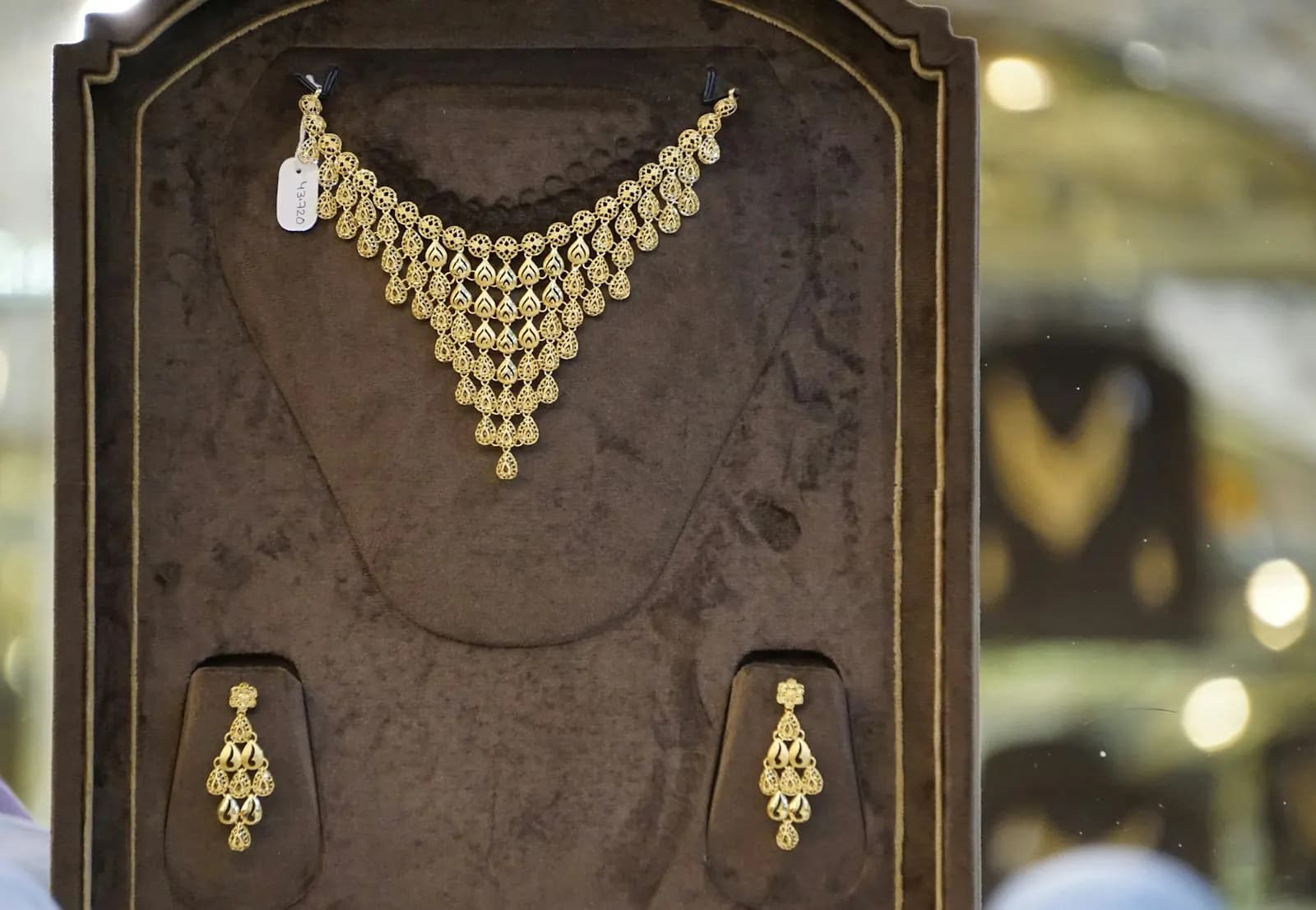A gold necklace and matching earrings displayed in a jeweller's showcase