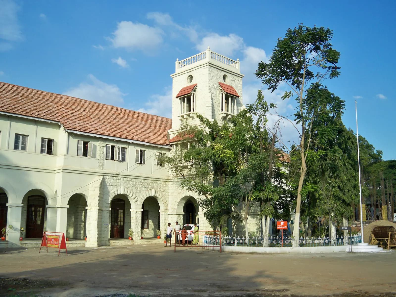 The white colonial-era main building and clock tower of Coimbatore Medical College Hospital under a blue sky