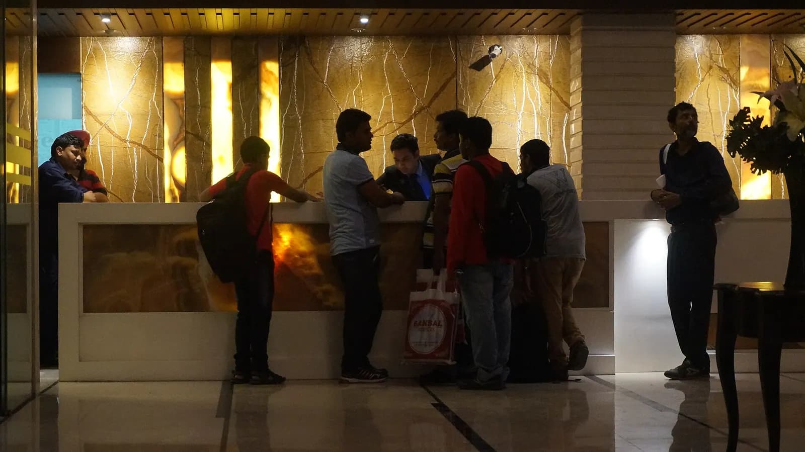 Guests with backpacks checking in at the marble reception desk of a four-star hotel in Chandigarh