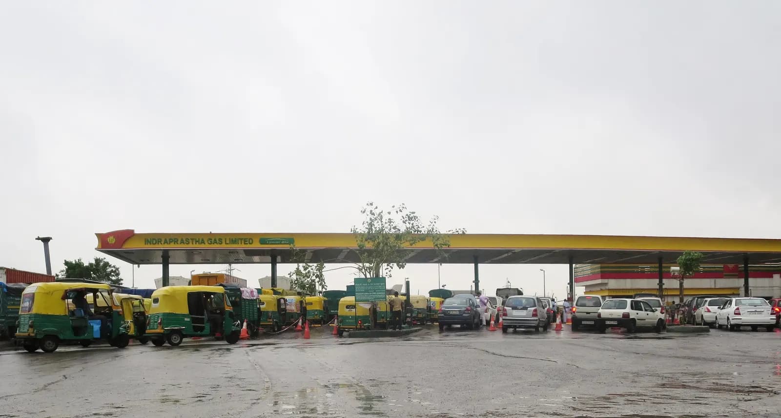 Long queue of auto-rickshaws and cars waiting under the canopy of a CNG filling station in Delhi