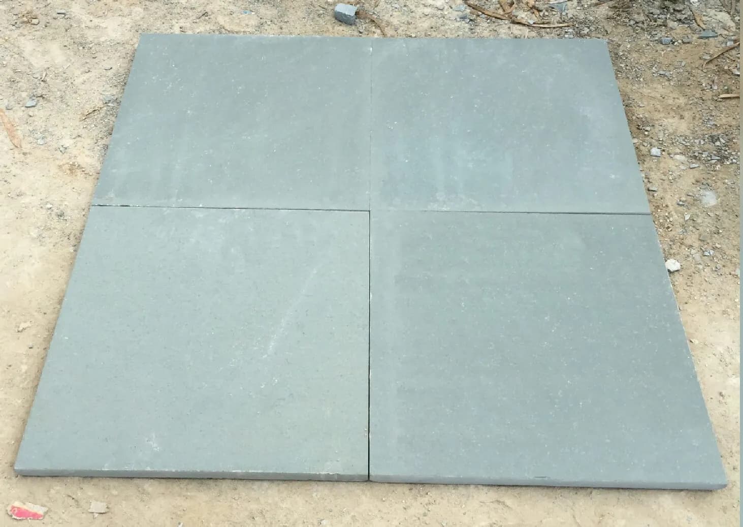 Four square slabs of rough-finish grey-green Kota stone laid on the ground