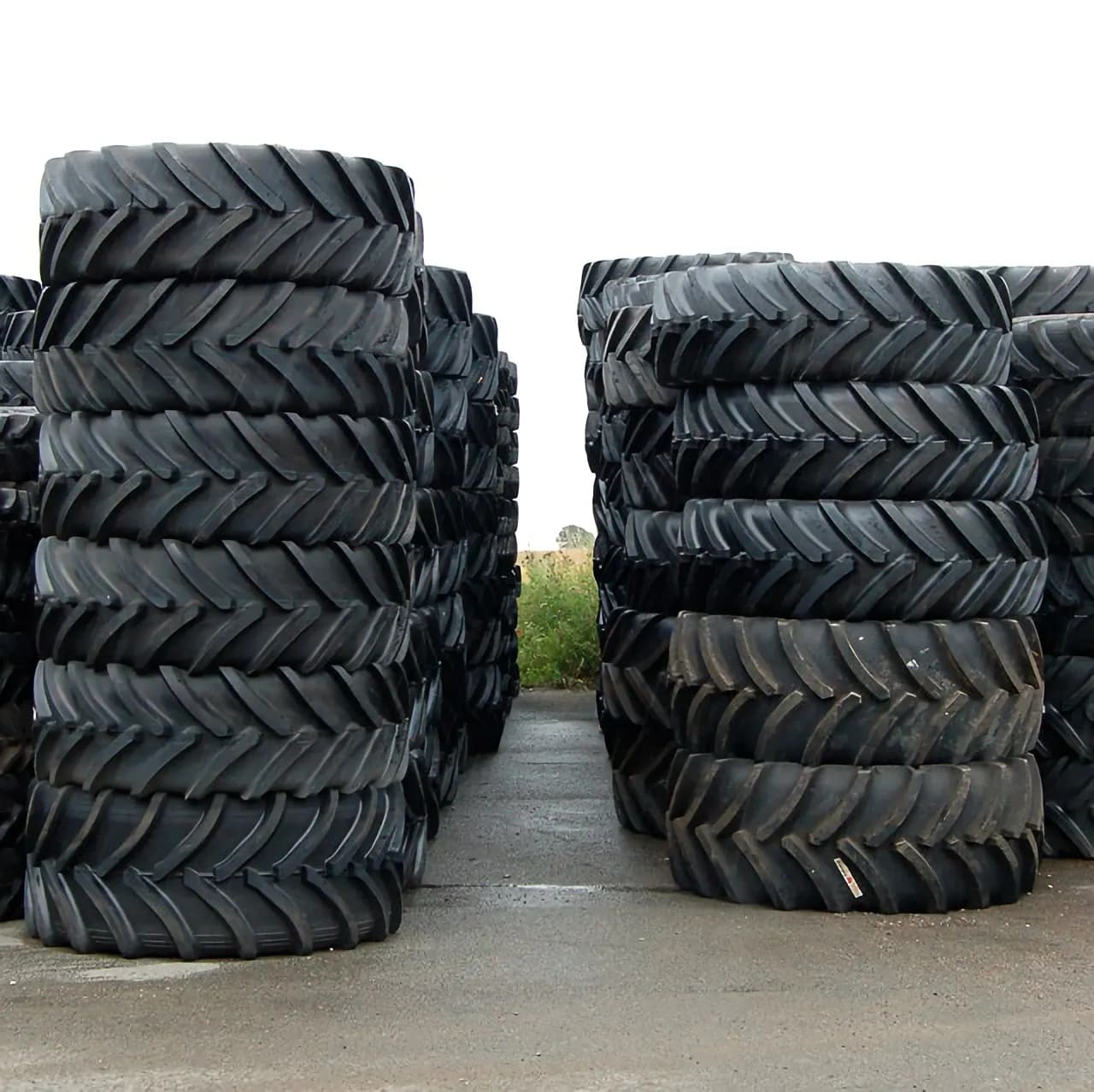 Stacks of new tractor tyres with deep lug treads stored outdoors