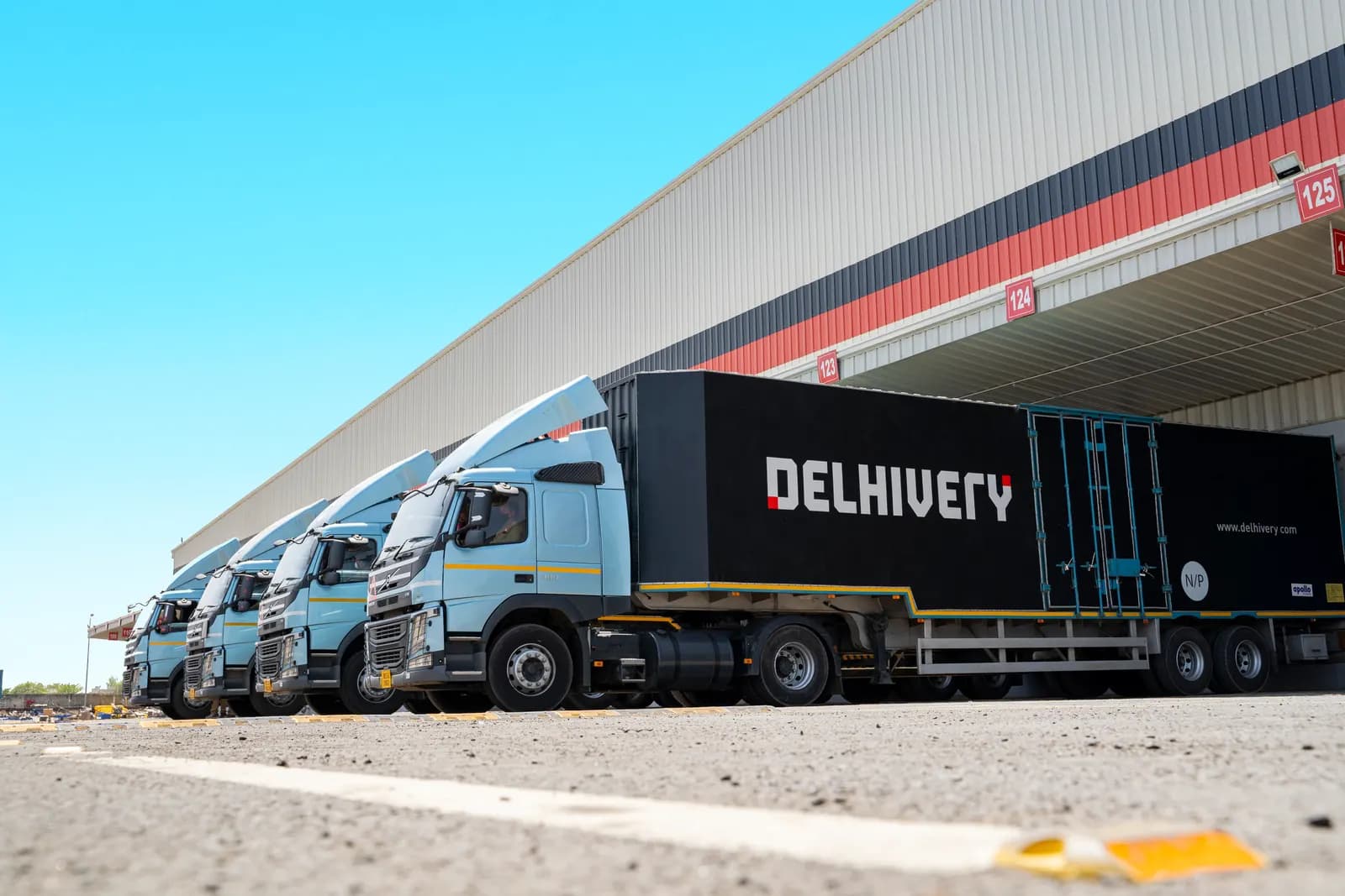 Line of logistics trucks parked at the loading docks of a large warehouse in India