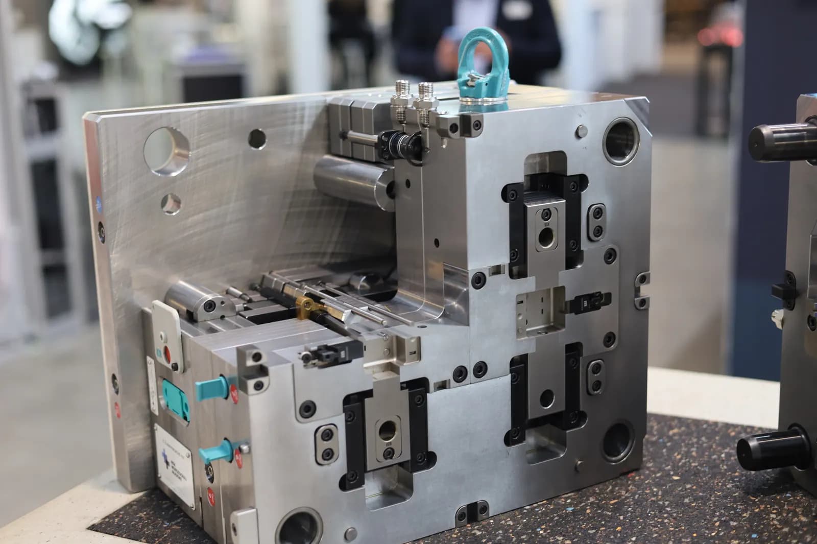 A two-half steel plastic injection mould with cooling connectors, guide pillars and a lifting eye on display