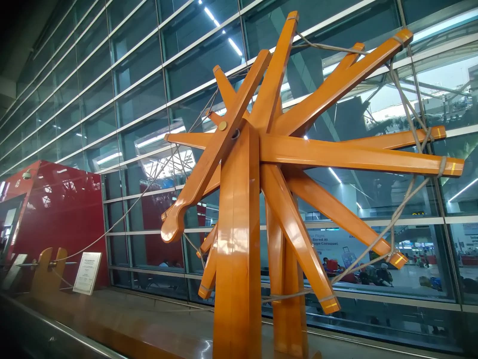 A giant wooden charkha spinning-wheel sculpture displayed in an airport terminal in India