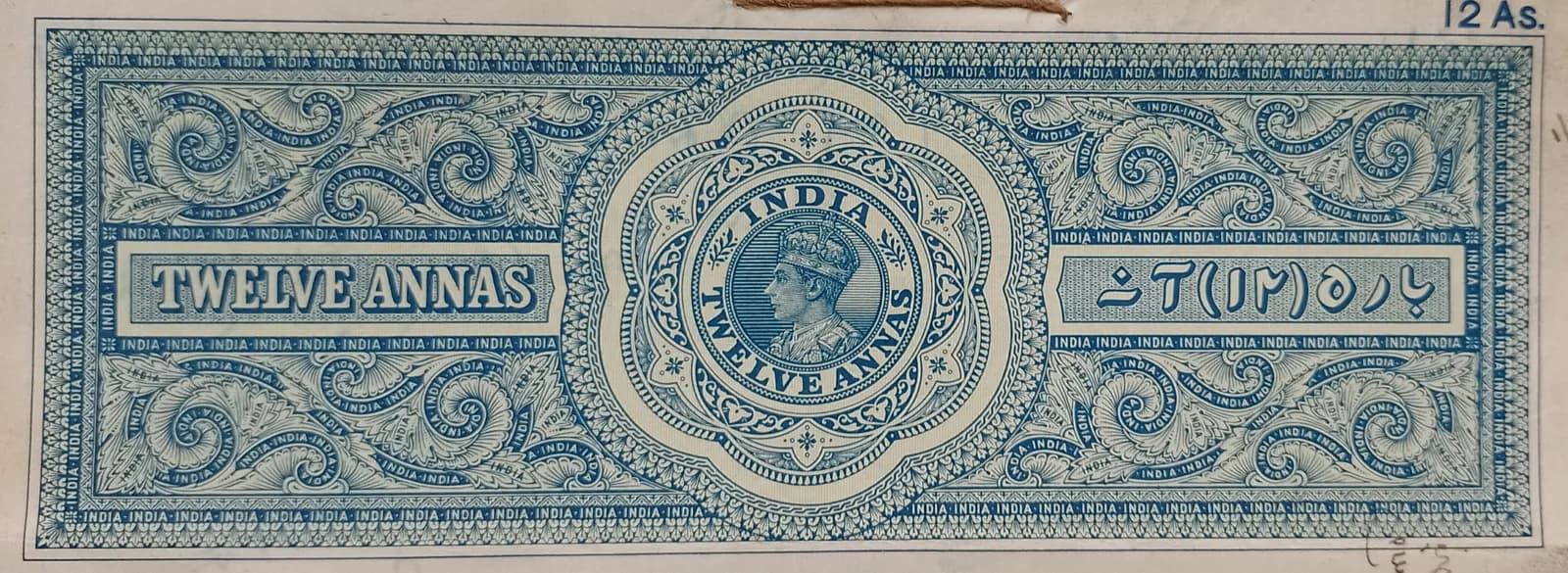 An old blue British India stamp paper with the words Twelve Annas engraved on it