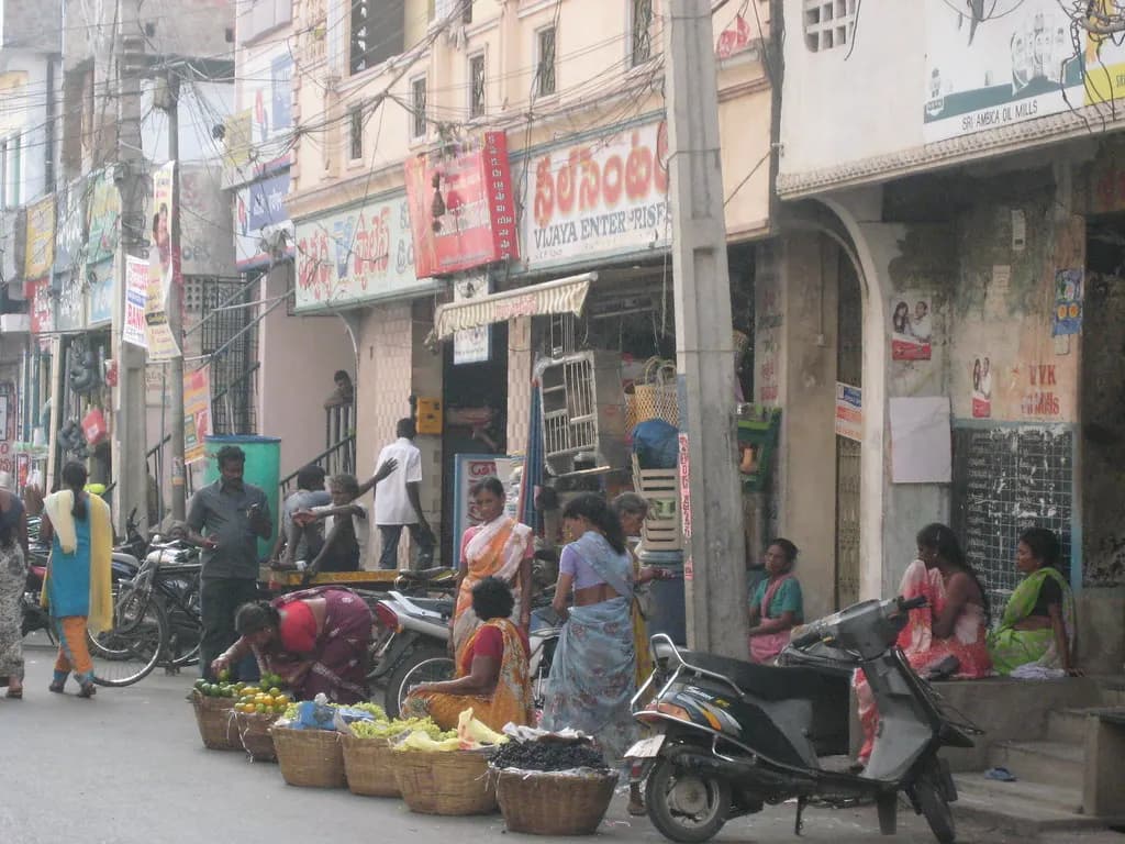 Street of small shops in Vijayawada with vegetable sellers on the pavement
