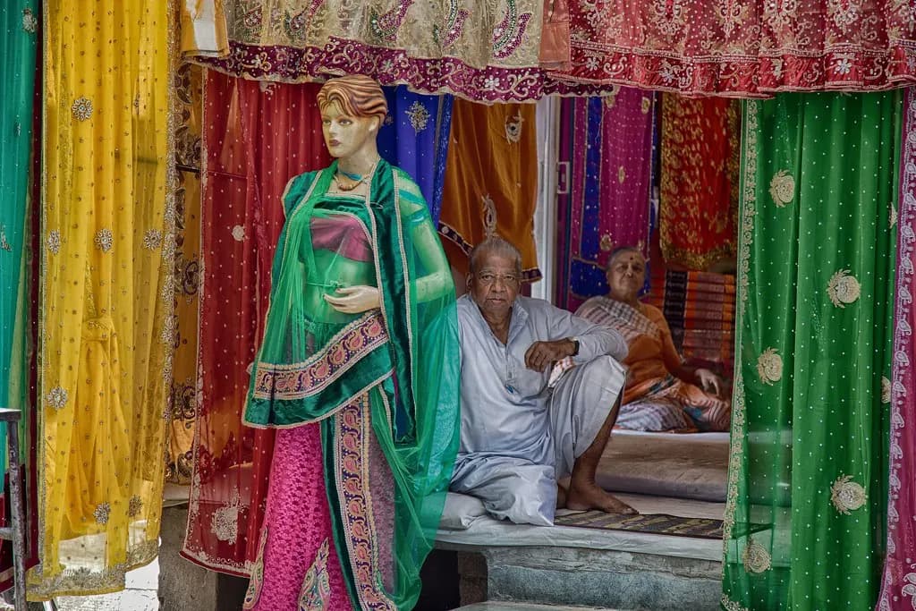 Two shopkeepers in traditional dress waiting for customers at a cloth shop in Indore's cloth market