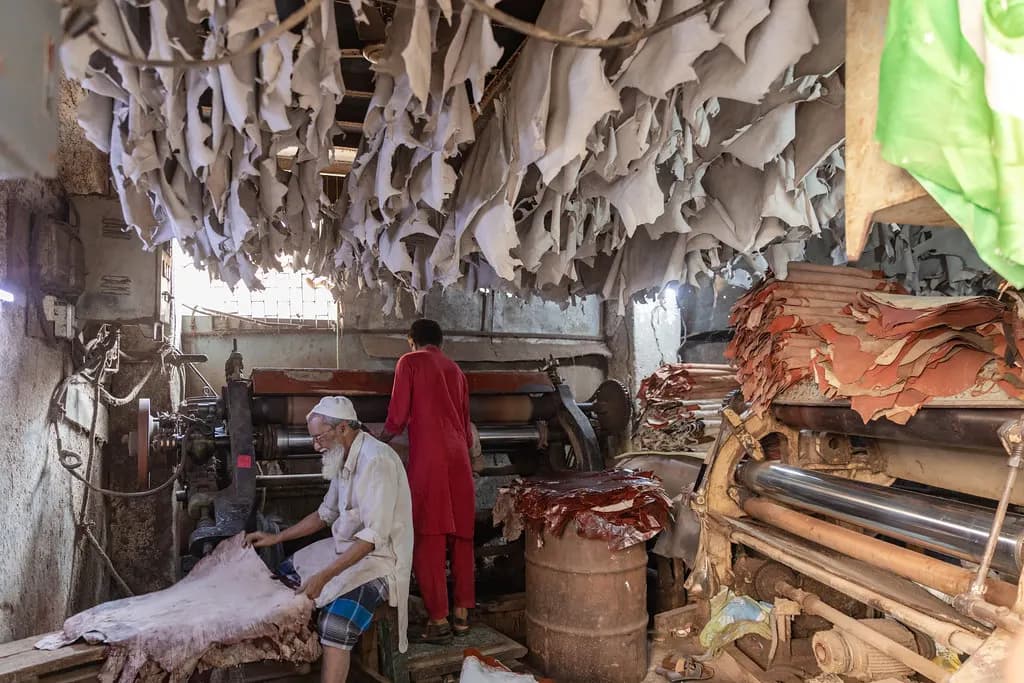 A worker processing leather hides on machinery in a small workshop in Dharavi, Mumbai