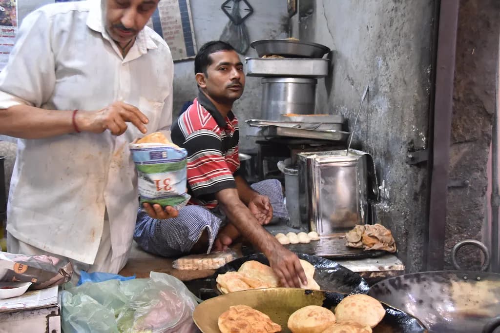 Two cooks frying pooris at a small sweet shop kitchen in Amritsar, Punjab