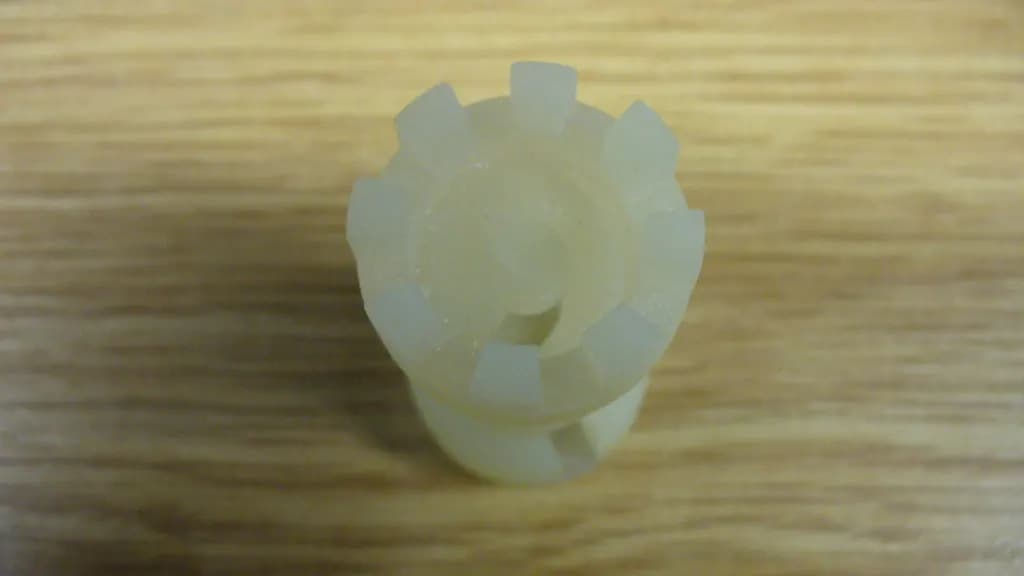 A small 3D-printed plastic prototype part on a wooden table