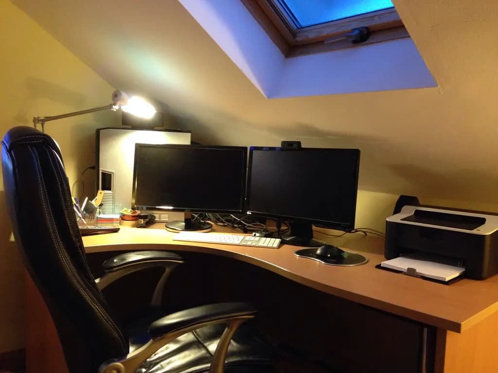 A single-person home office with a desk, two monitors and a printer