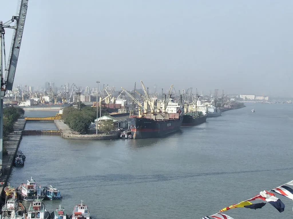 Cargo ships berthed along the quay at Mumbai docks with cranes and the city skyline behind