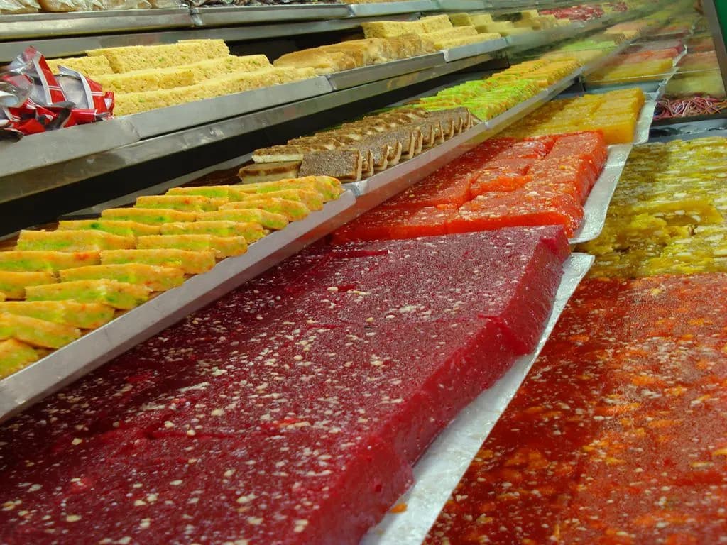 Trays of colourful Bengali sweets in the glass counter of a Kolkata sweet shop