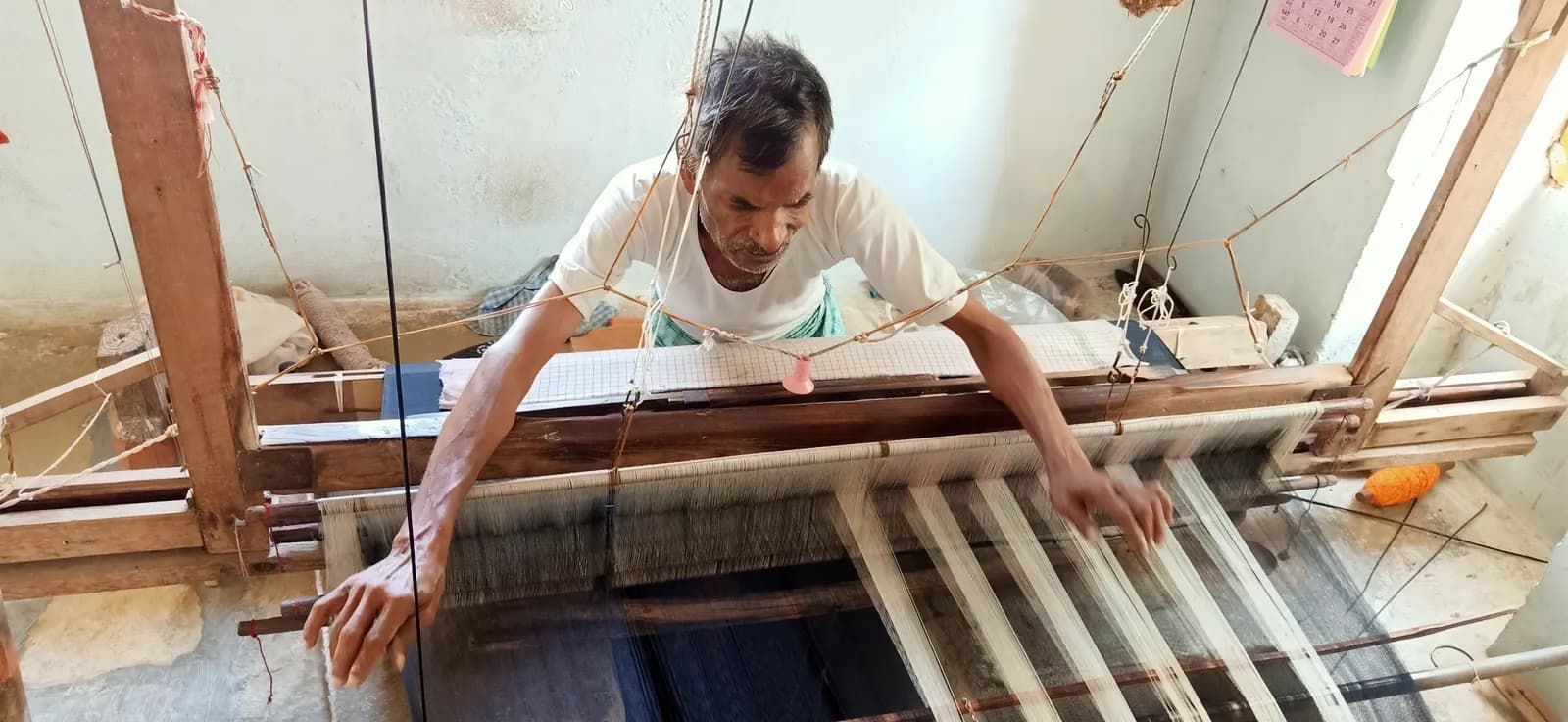 A weaver working a wooden handloom to make a saree