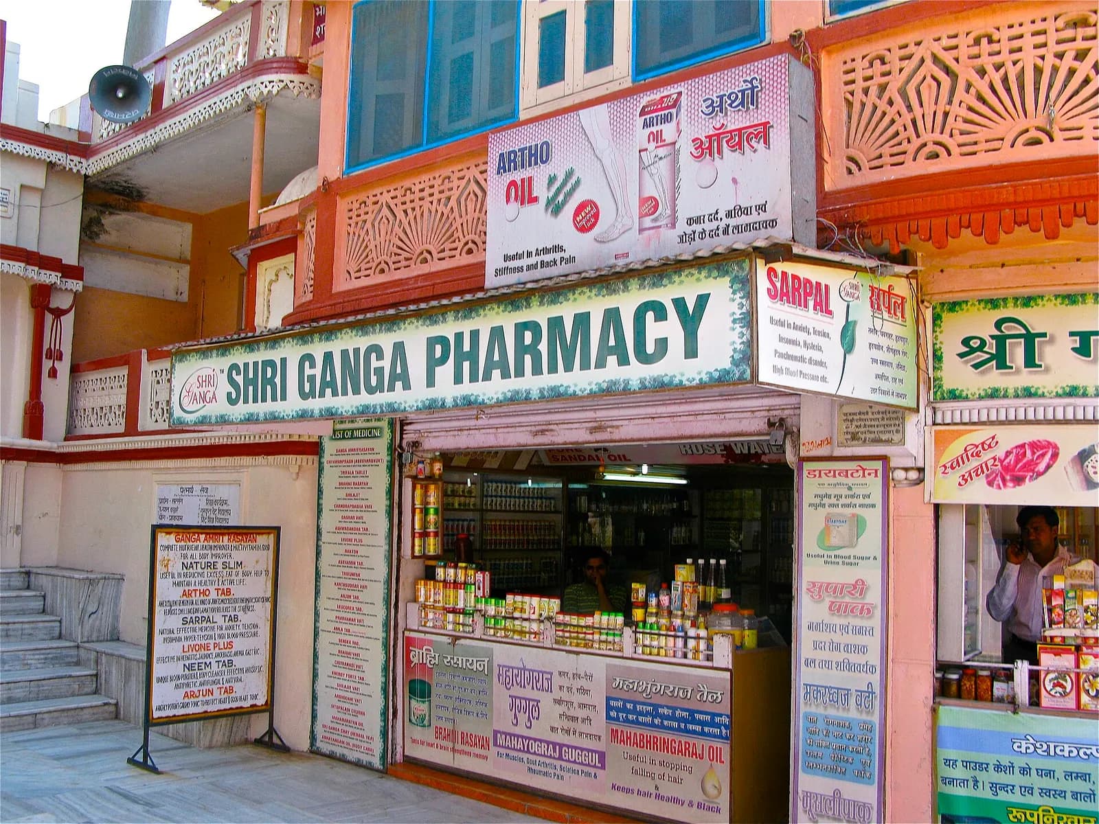 The front of an Ayurvedic pharmacy in Rishikesh, with glass counters, shelves of medicines and hand-painted signboards
