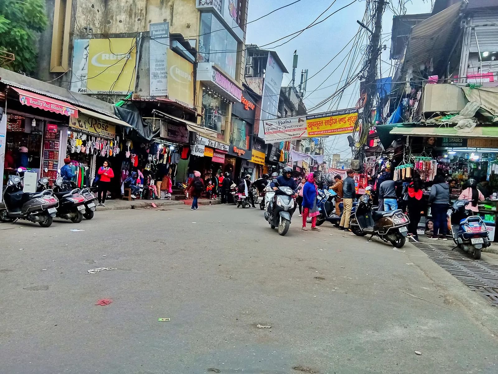 Paltan Bazaar in Dehradun, a wide shopping street lined with clothing and general stores, with scooters parked along both sides