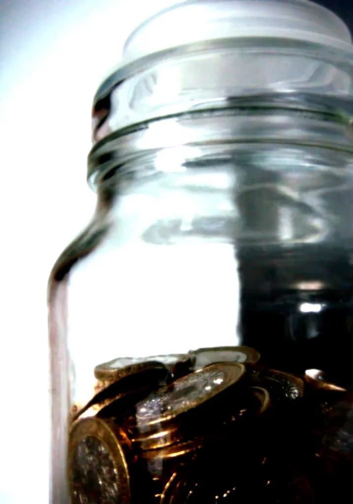 A glass jar holding a layer of pound coins