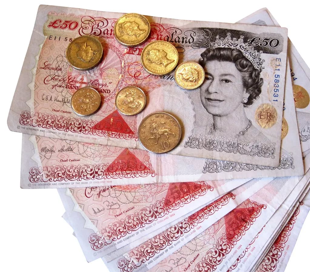 Fifty-pound notes and pound coins spread on a table