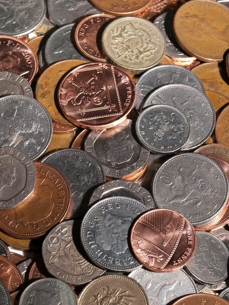 A close-up pile of British coins including pounds, 50p, 20p and copper pennies