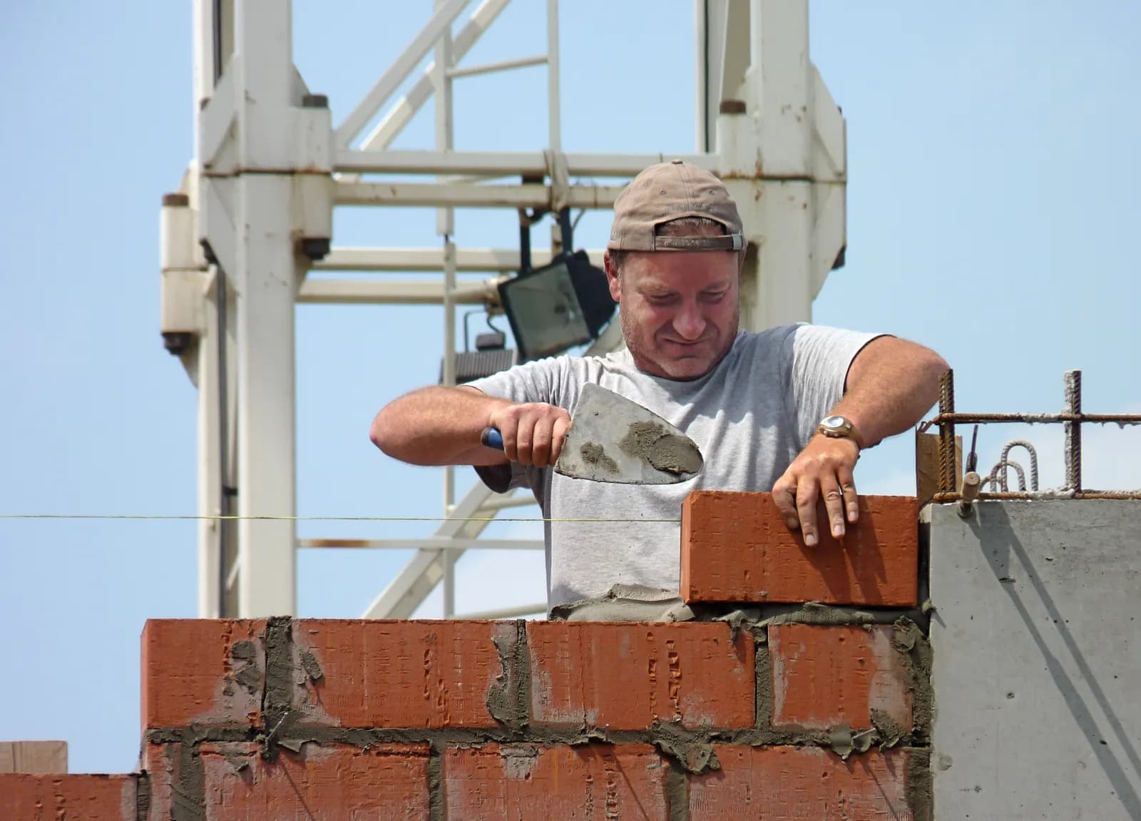 A bricklayer laying bricks with a trowel on a building site
