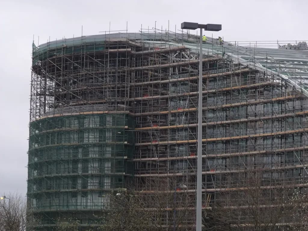 A college building under construction in West Bromwich with steel frame, cranes and site hoarding