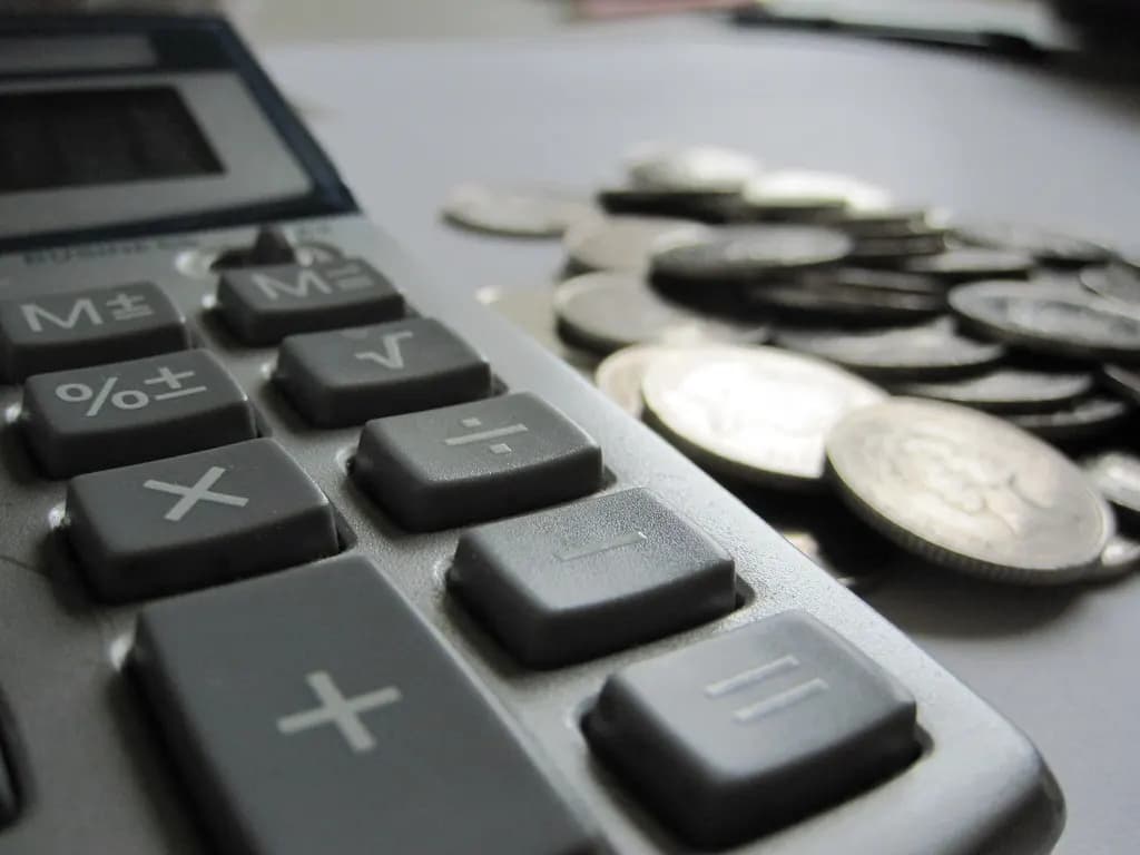Close-up of calculator keys beside a pile of British coins