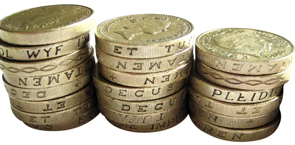 Three stacks of round British one-pound coins on a white background