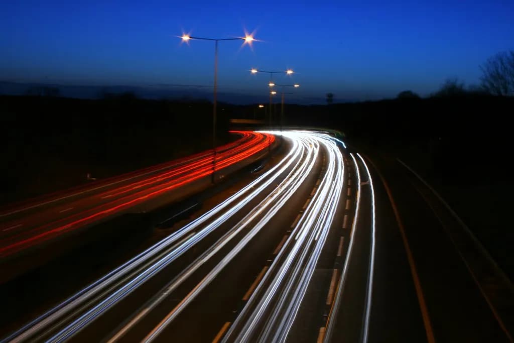 Traffic light trails on the M25 motorway at dusk under a deep blue sky