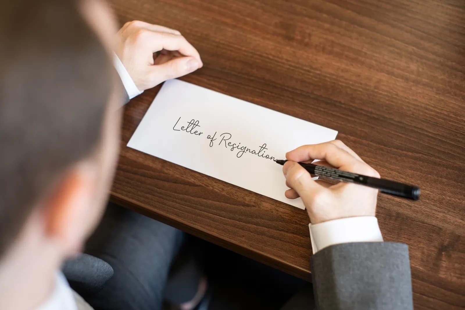 Someone writing the words Letter of Resignation on an envelope at a desk