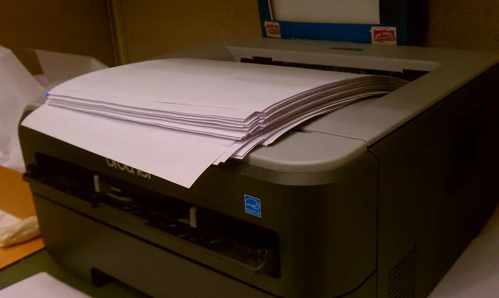 Office laser printer with a stack of printed paper on its output tray