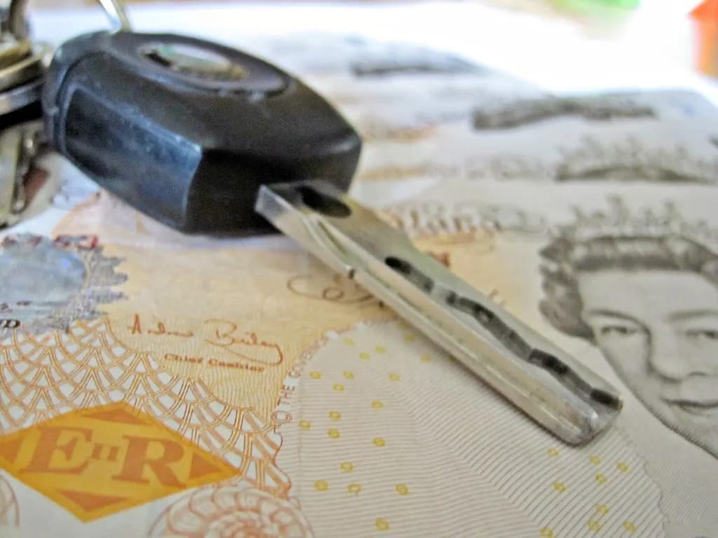 A car key resting on a spread of British pound notes