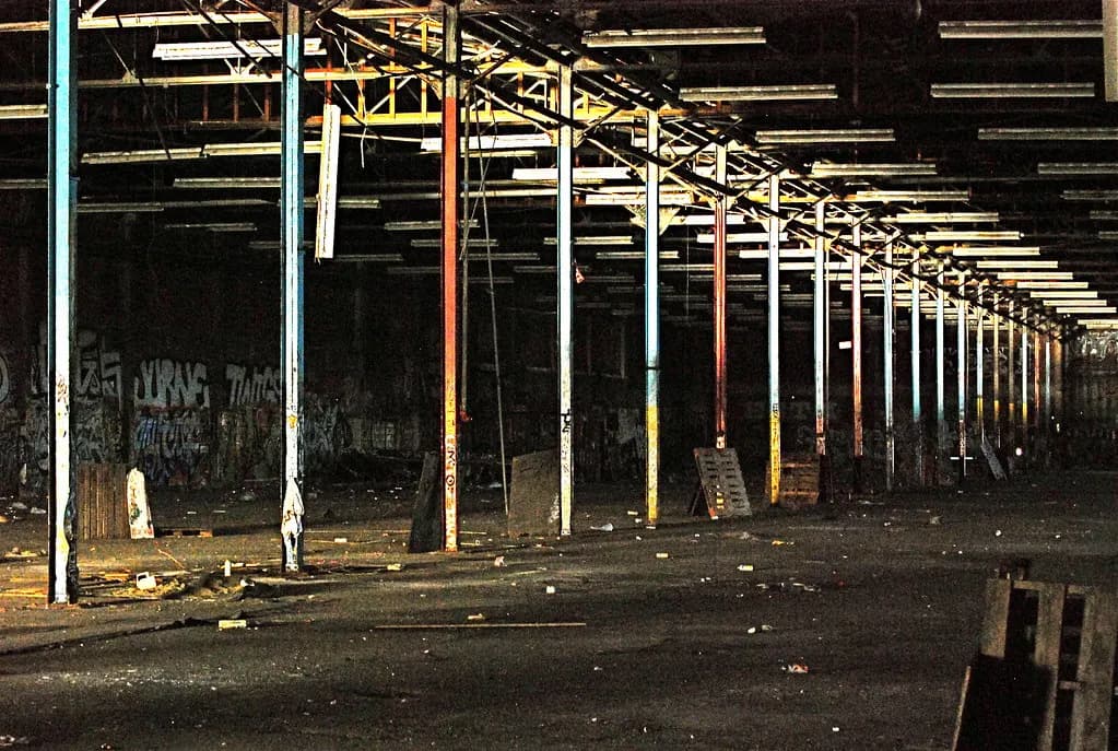 Empty disused warehouse with rows of steel columns and bare concrete floor