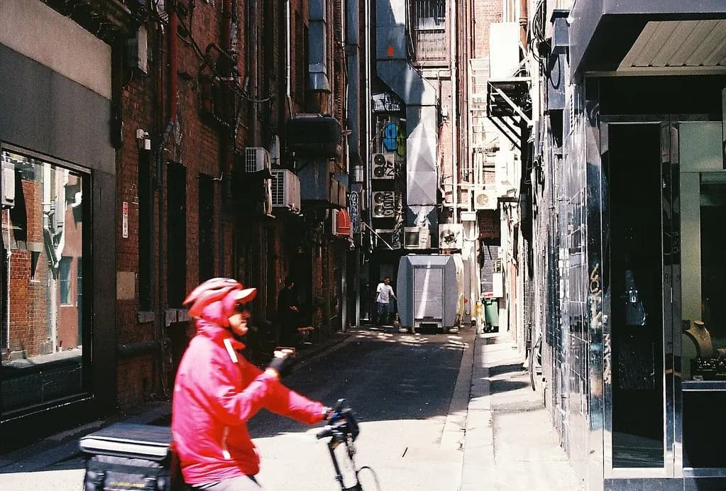 Food delivery rider on an electric bike with an insulated box riding through a city alley