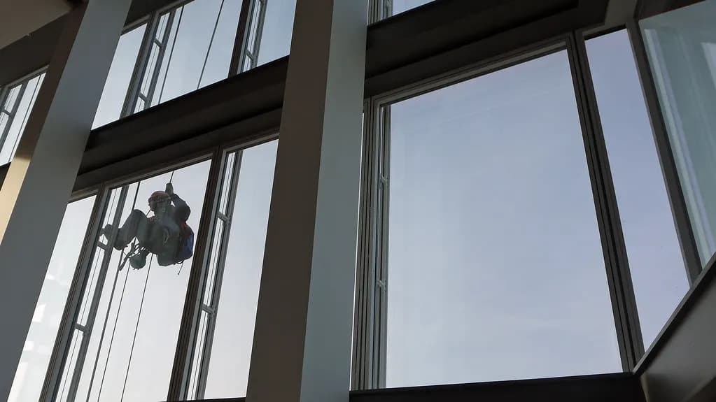 A rope-access window cleaner working on the glass facade of a tall building