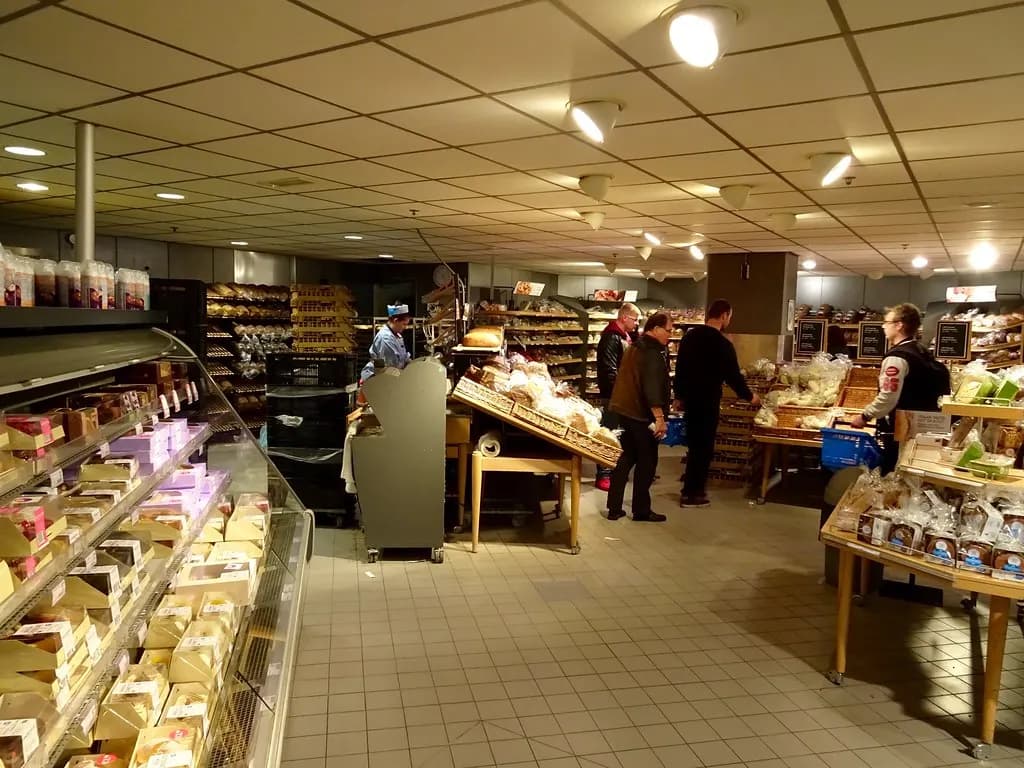 Customers choosing bread and cakes on the shop floor of a bakery