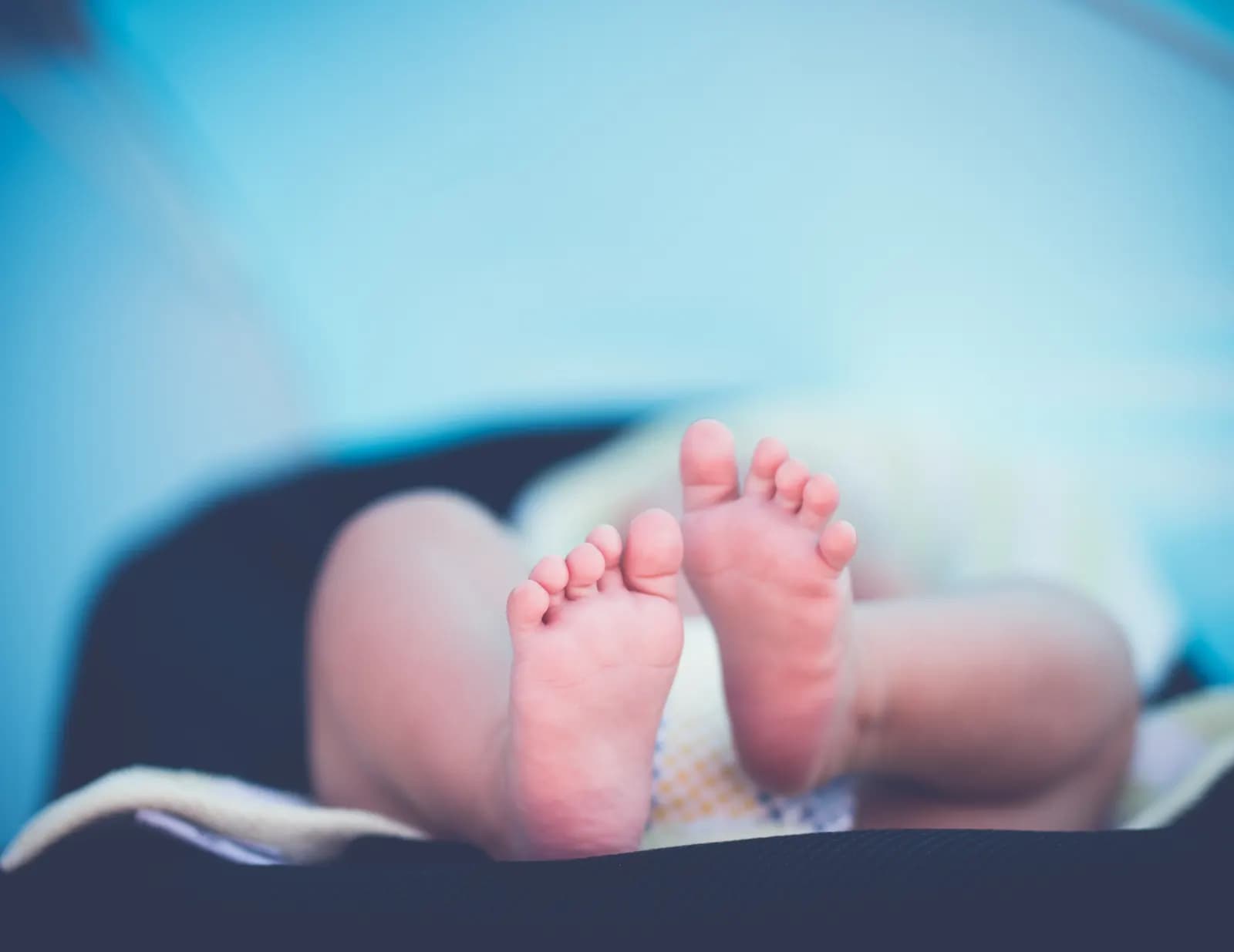 A newborn baby's bare feet resting on a soft blanket