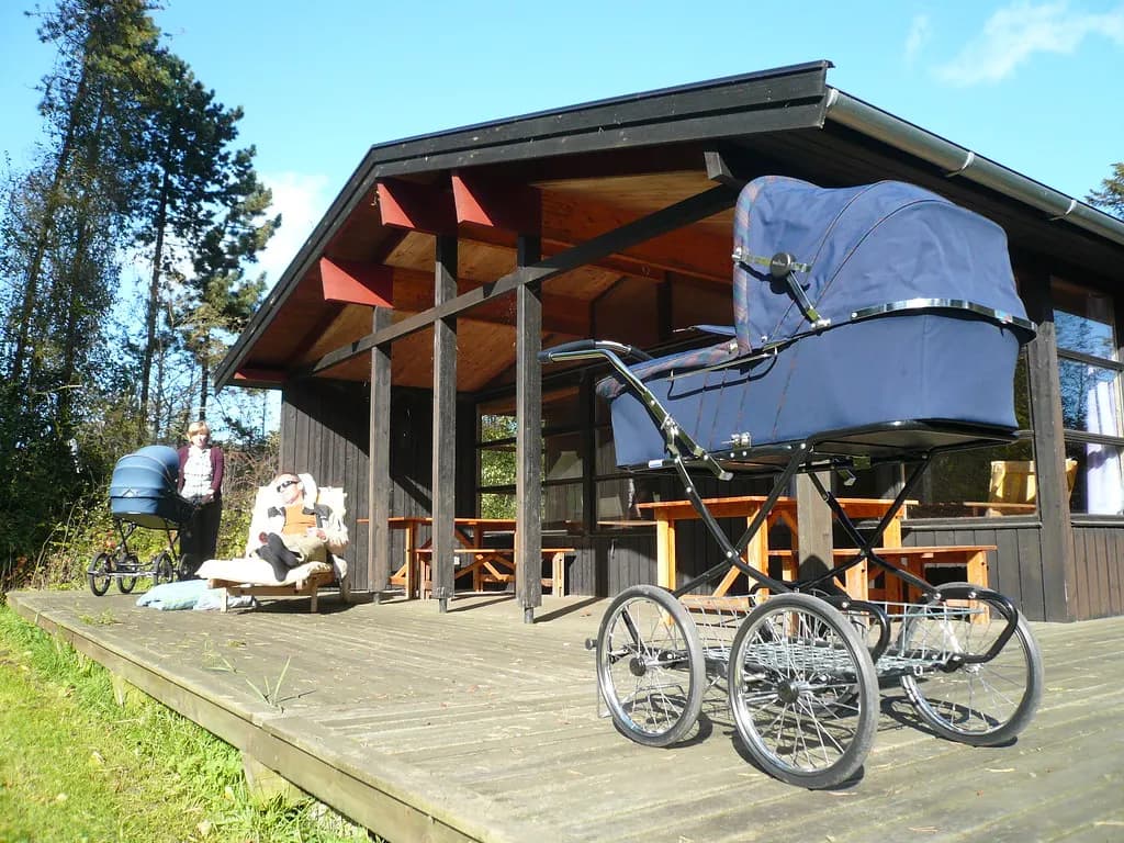 Large navy baby prams parked on a wooden deck outside a nursery building