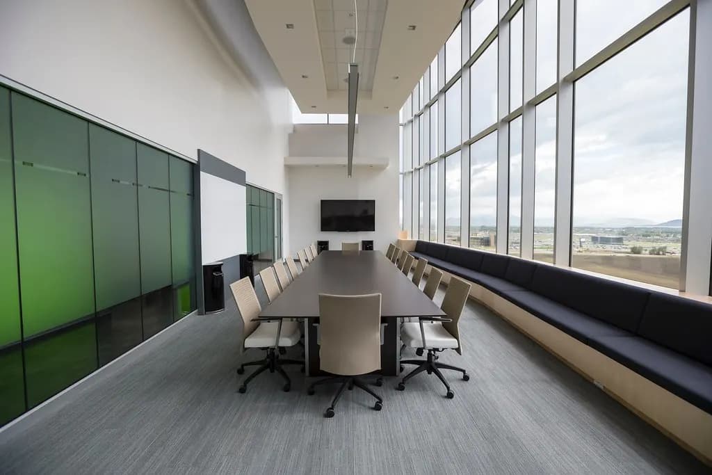 An empty meeting room with a long table, chairs and a wall of windows