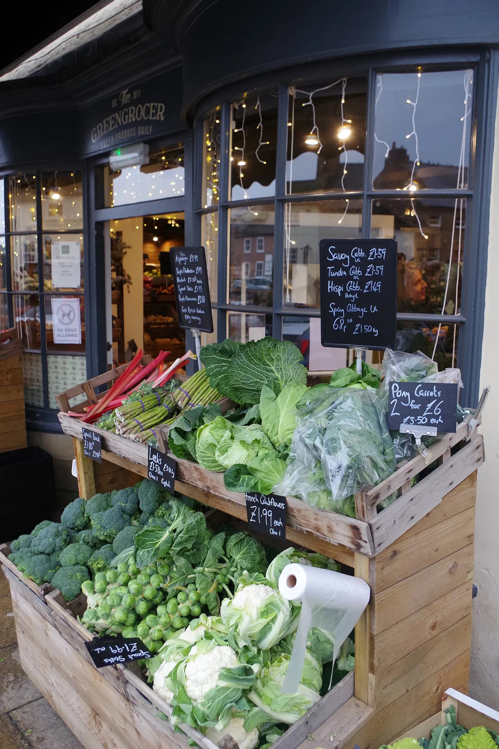 Crates of cabbages, cauliflowers, sprouts and carrots with chalkboard prices outside The Greengrocer shop in Bedale, North Yorkshire