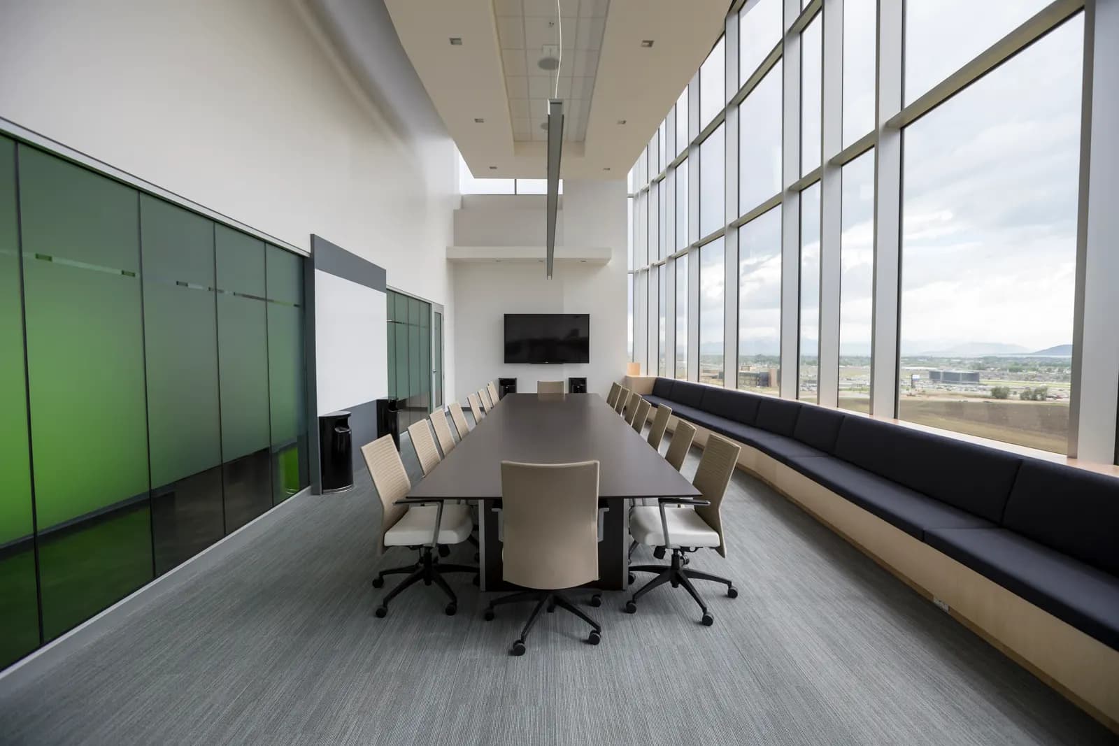 Empty corporate boardroom with a long table, office chairs and floor-to-ceiling windows