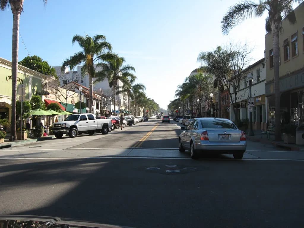 Palm-lined Main Street in downtown Ventura, California, with small shops and cafe umbrellas on both sides