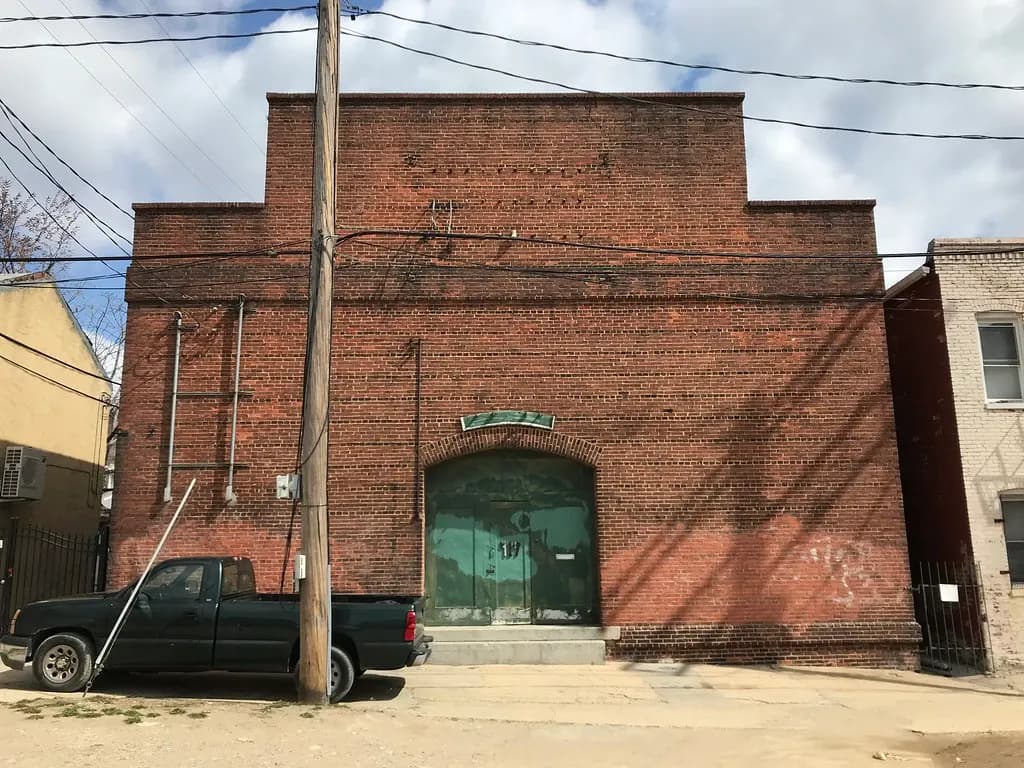 Old brick light-industrial building with an arched green door in Baltimore