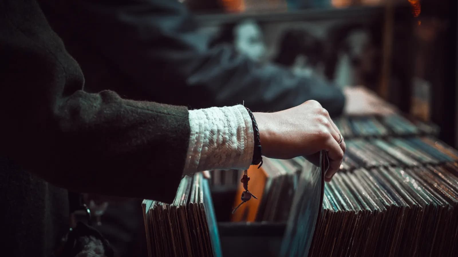 Hand flipping through vinyl records in a record store bin