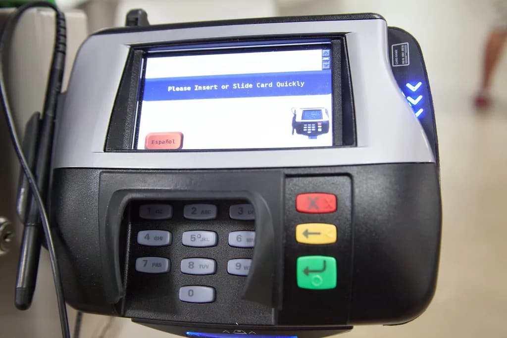 Countertop card payment terminal with a keypad and a screen prompting the customer to insert or swipe a card