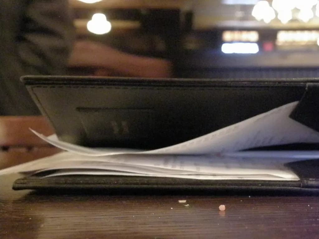 Restaurant check presenter folder with a bill and receipt slips on a table