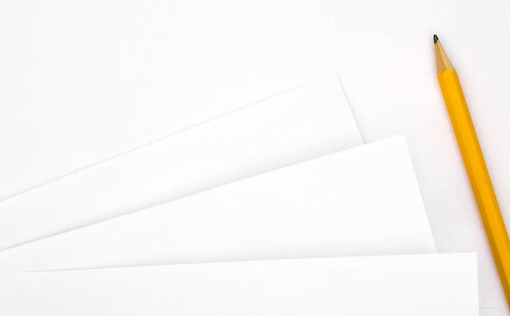 Blank sheets of paper fanned out beside a yellow pencil