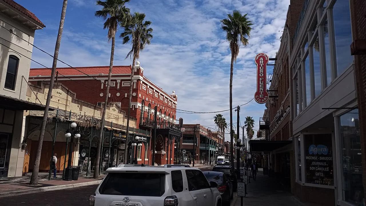 Shops and historic brick buildings along 7th Avenue in Ybor City, Tampa, with palm trees lining the street