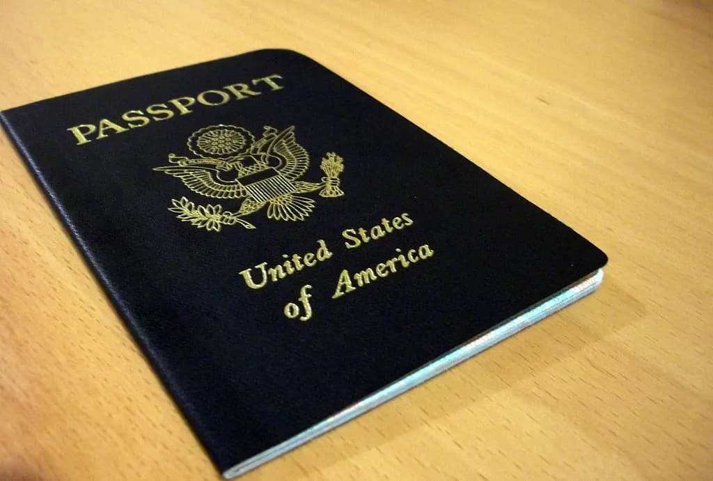 Closed navy blue United States passport with gold eagle seal lying on a wooden table