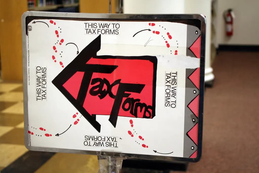 Hand-made red and white library sign with an arrow reading This way to tax forms